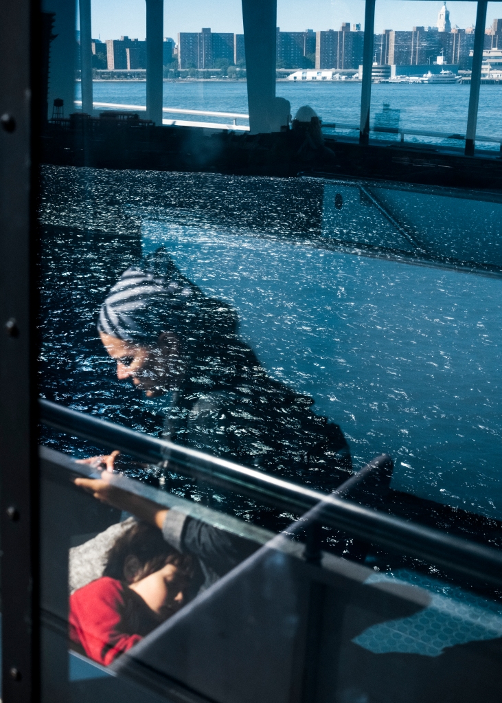 Mother and child on the ferry in New York City with skyline and water reflected in the windows